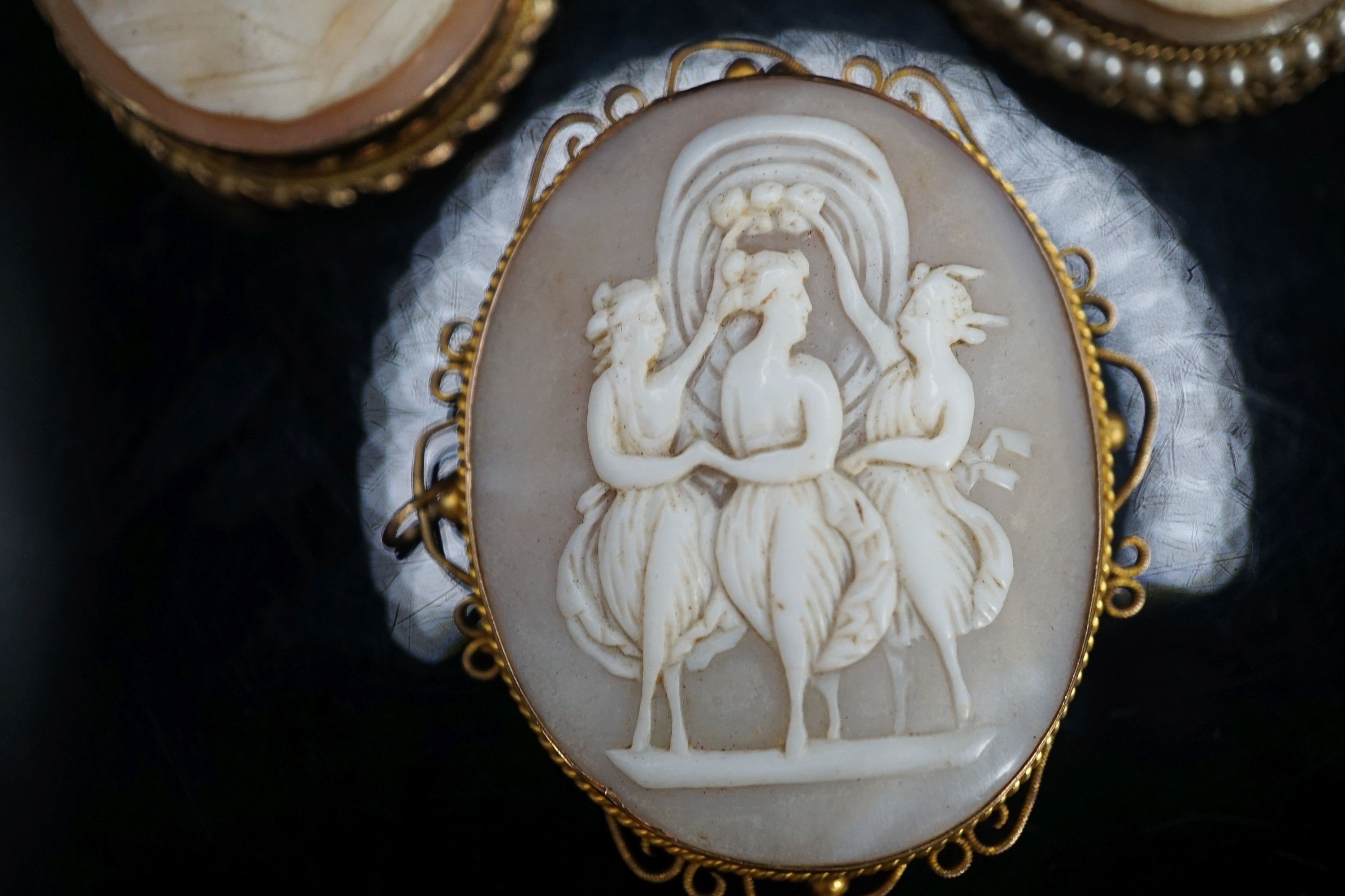 A Victorian 9ct mounted oval cameo shell brooch, one other later 9k mounted cameo brooch and a gilt metal mounted cameo brooch.